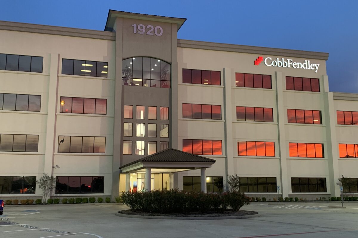 CobbFendley logo on outside of Pearland, TX office. a 4 story tan building with red glow on windows