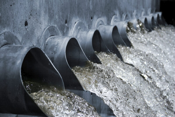 a close up of storm water running rapidly out of multiple drainage pipes