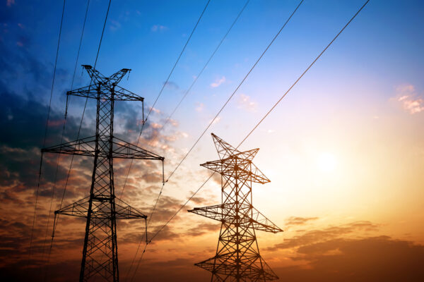 high voltage transmission towers with power lines at sunset with blue and orange sky