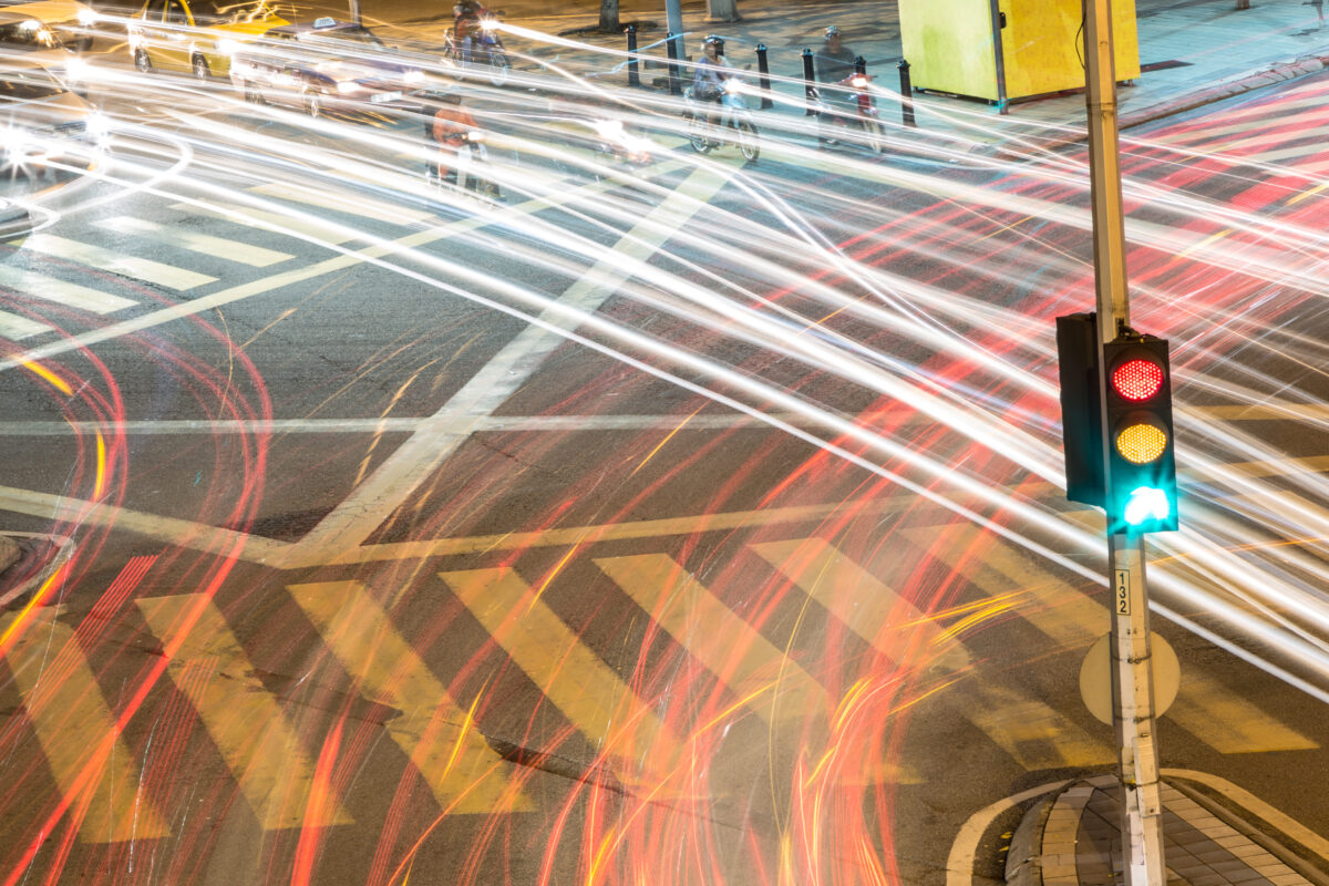 traffic light at intersection with pedestrian photos. time lapsed so that there are streaks of light from passing cars taillights and headlights