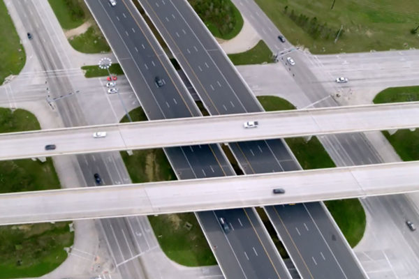 An aerial view of a highway intersection with elevated roadways and surface/service streets below.