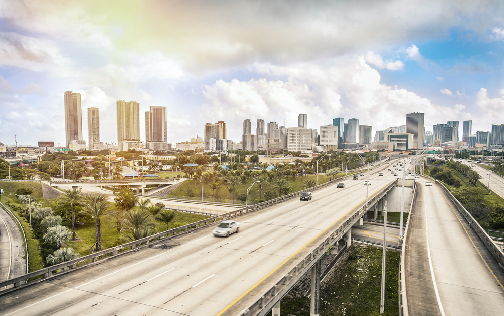 skyline of Miami on a partly cloudy day with view of roadway bridge with traffic passing